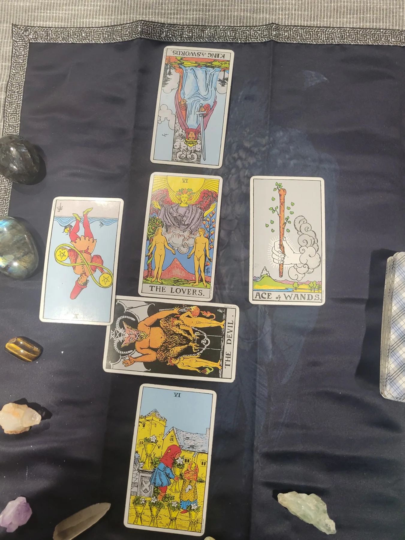 Tarot cards laid in a spread on navy fabric, surrounded by crystals.